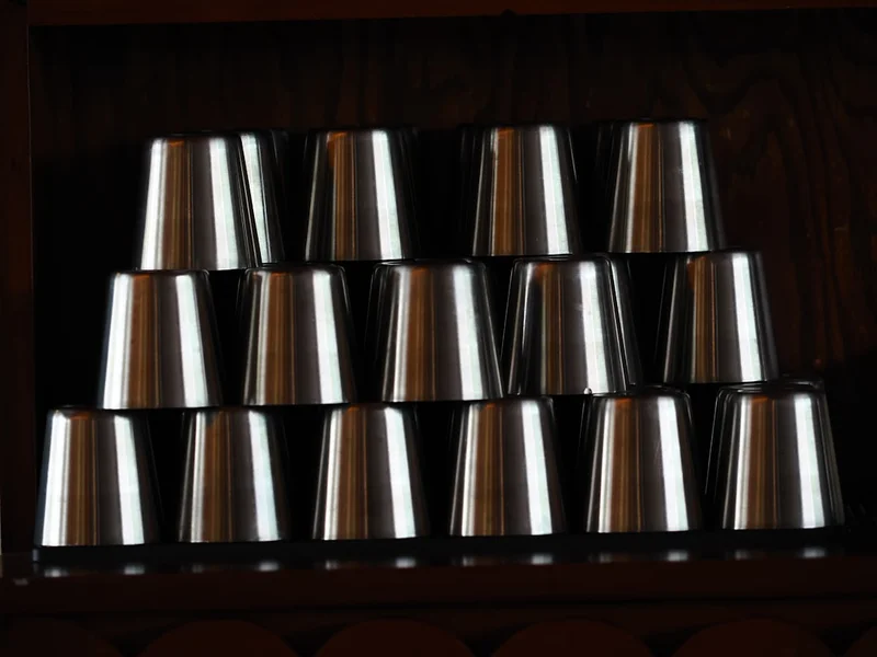 Stack of metal cups arranged neatly on a shelf.